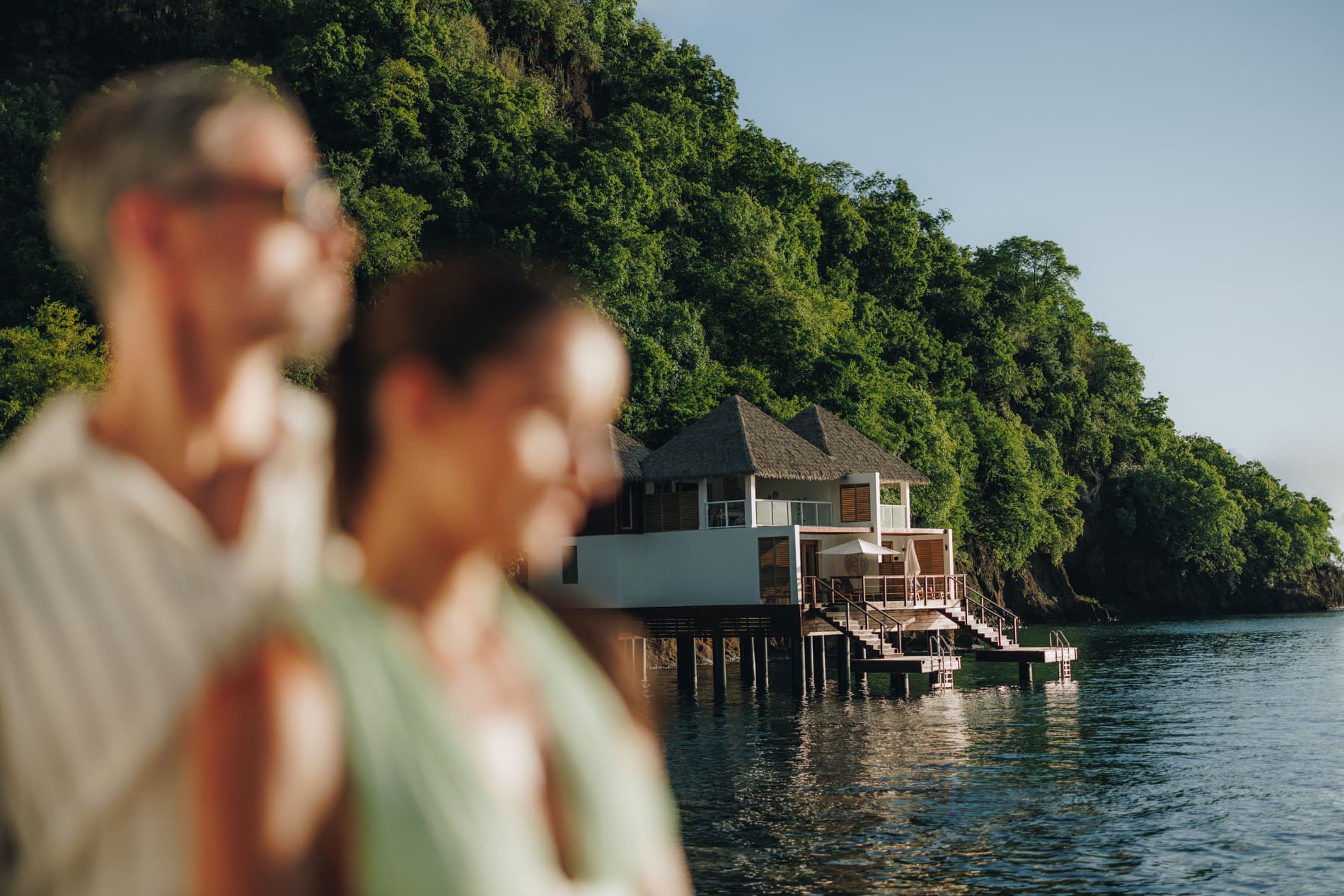 A couple looking toward overwater villas at Sandals Saint Vincent